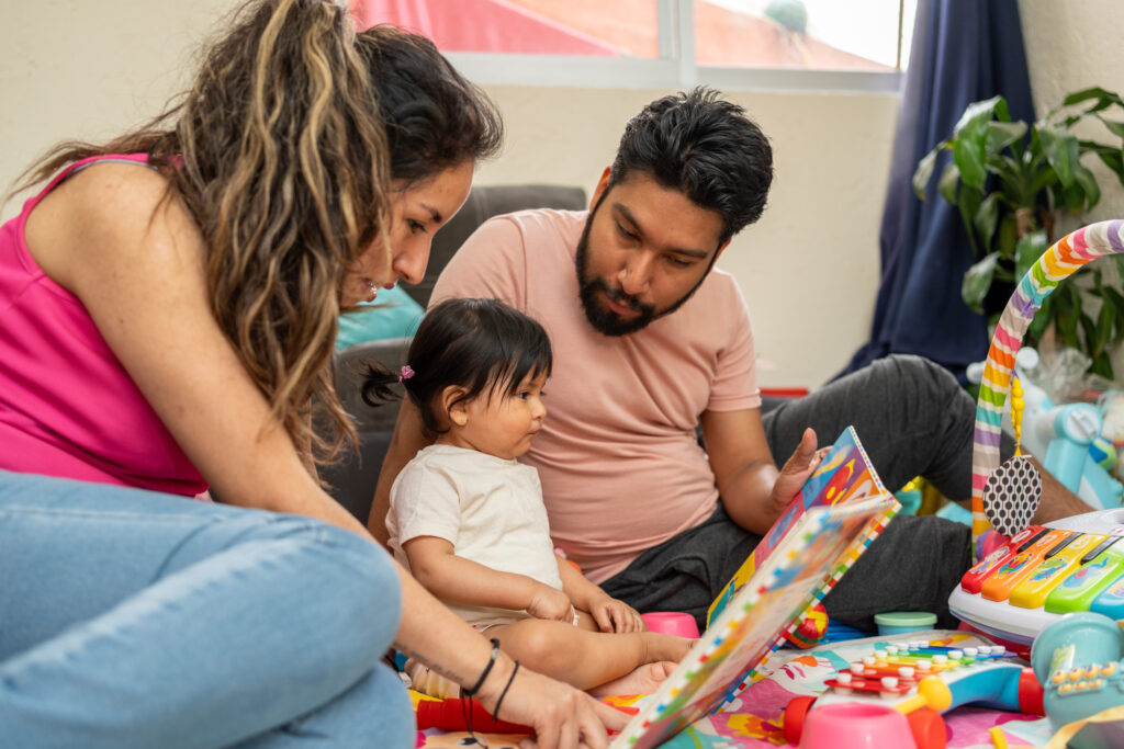 Two adults sharing a picture book with a young child